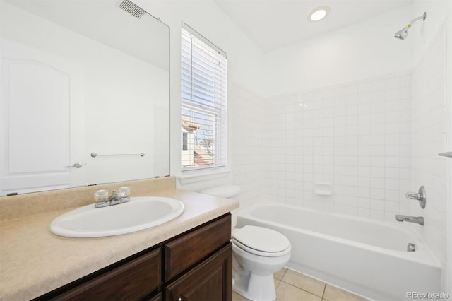 full bathroom featuring tile patterned flooring, vanity, tiled shower / bath combo, and toilet