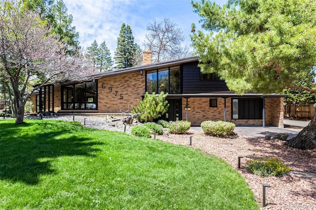back of property with a yard, brick siding, and a chimney