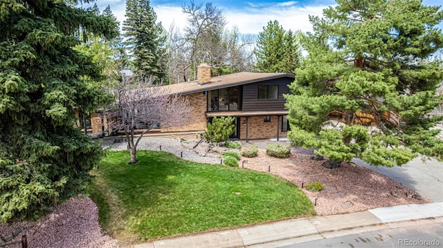 view of front of property featuring brick siding, a front lawn, and a chimney