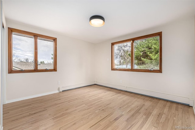 spare room featuring baseboards and light wood finished floors