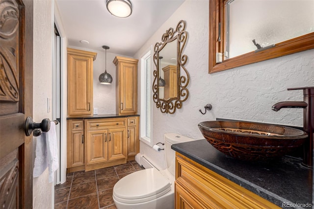 bathroom with vanity, a baseboard radiator, a textured wall, and toilet