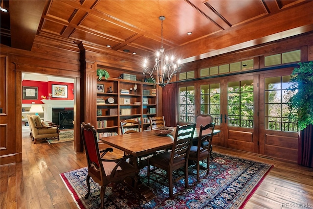 dining area with wood walls, french doors, wood ceiling, hardwood / wood-style flooring, and a notable chandelier