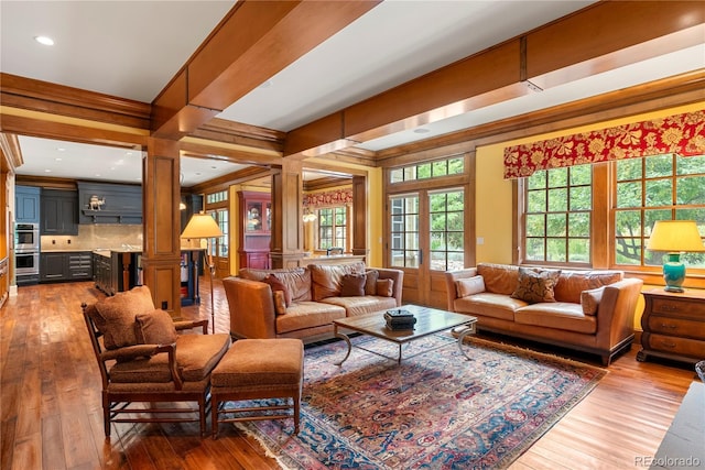 living area with wood-type flooring, recessed lighting, ornamental molding, and decorative columns