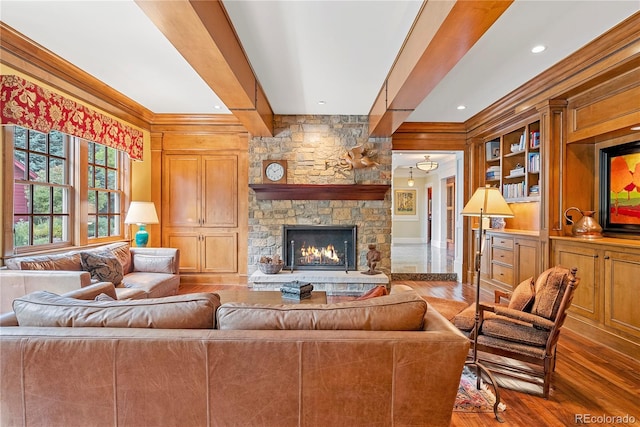 living area featuring a fireplace, wood finished floors, beam ceiling, and ornamental molding