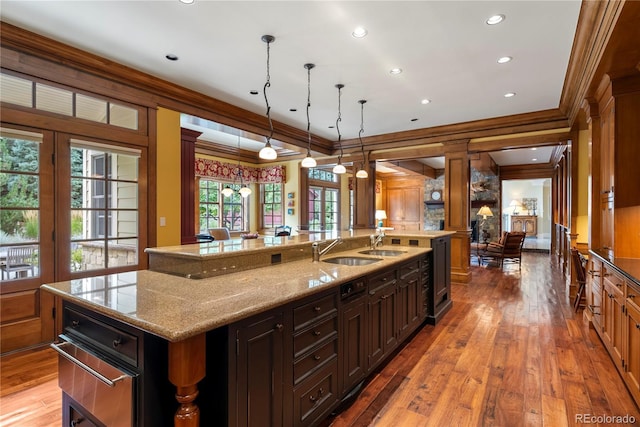 kitchen featuring light wood-style flooring, a sink, a large island, crown molding, and decorative light fixtures