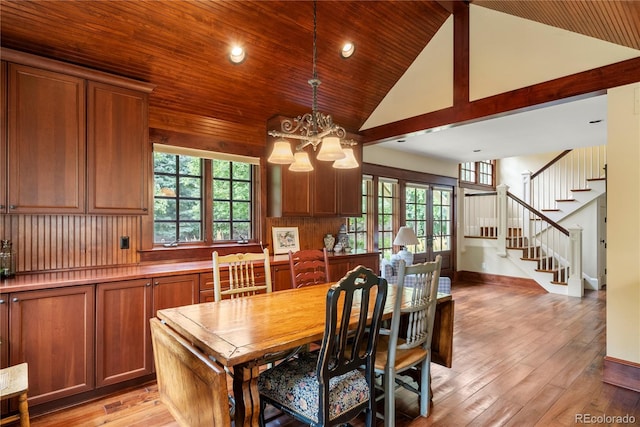 dining area featuring light wood finished floors, an inviting chandelier, stairs, wooden ceiling, and high vaulted ceiling