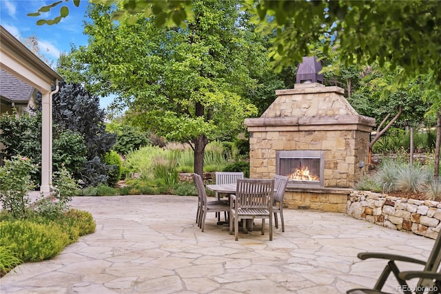 view of patio with an outdoor stone fireplace and outdoor dining space