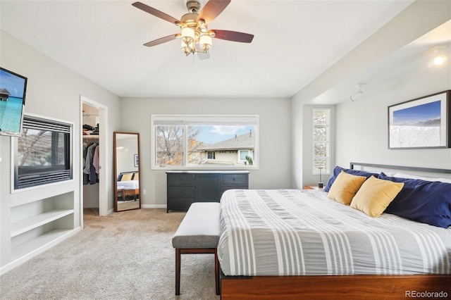 bedroom with a walk in closet, a ceiling fan, a closet, baseboards, and light colored carpet