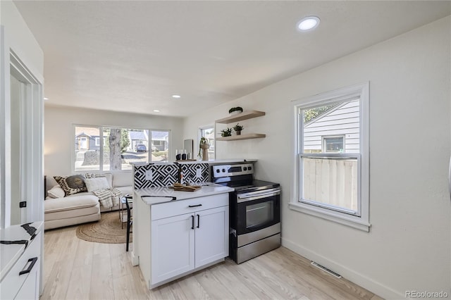 kitchen with electric range, light hardwood / wood-style floors, and white cabinetry