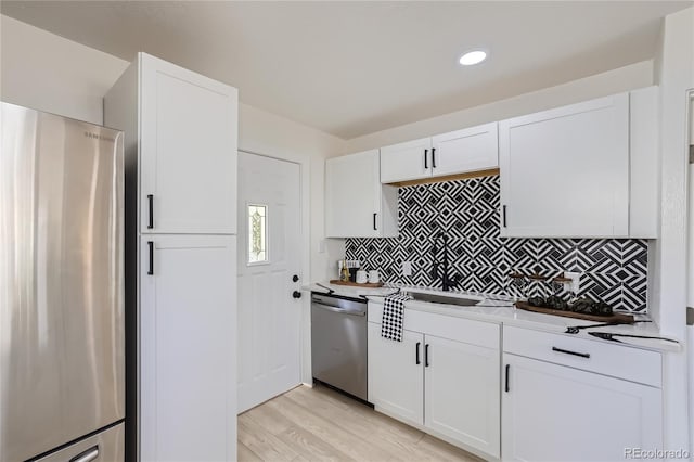 kitchen with tasteful backsplash, light hardwood / wood-style flooring, white cabinets, and stainless steel appliances