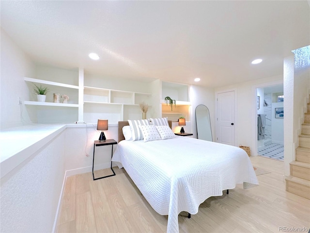 bedroom with connected bathroom and light hardwood / wood-style flooring