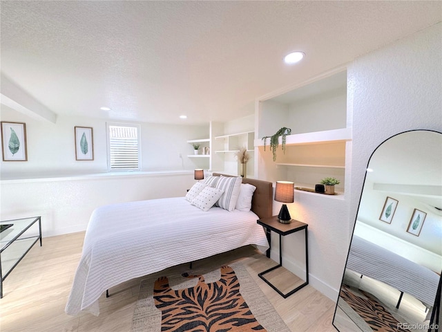 bedroom featuring a textured ceiling and light hardwood / wood-style flooring