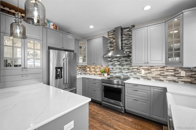kitchen with wall chimney range hood, appliances with stainless steel finishes, decorative backsplash, and gray cabinetry