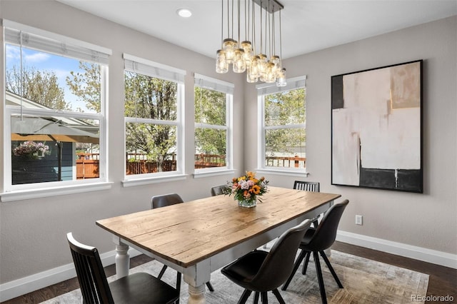 dining space with a chandelier, baseboards, and dark wood-type flooring