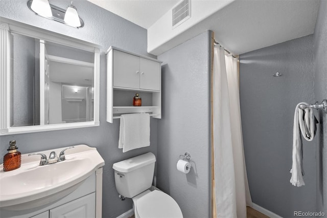 full bath featuring toilet, a shower with curtain, visible vents, a textured wall, and vanity
