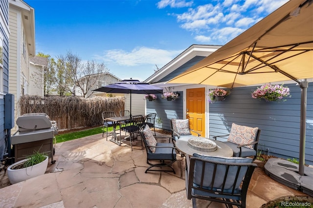 view of patio with outdoor dining space, grilling area, and fence
