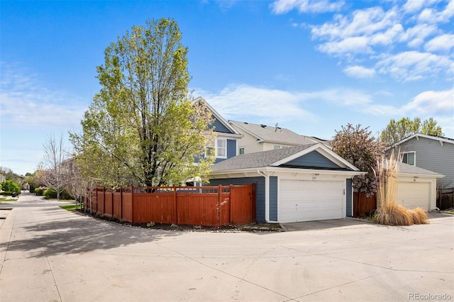 view of side of home featuring driveway, fence, and a garage