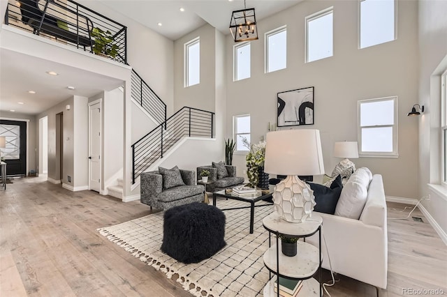 living room with a high ceiling, an inviting chandelier, and light wood-type flooring