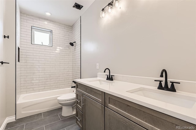 full bathroom featuring vanity, tiled shower / bath, and toilet