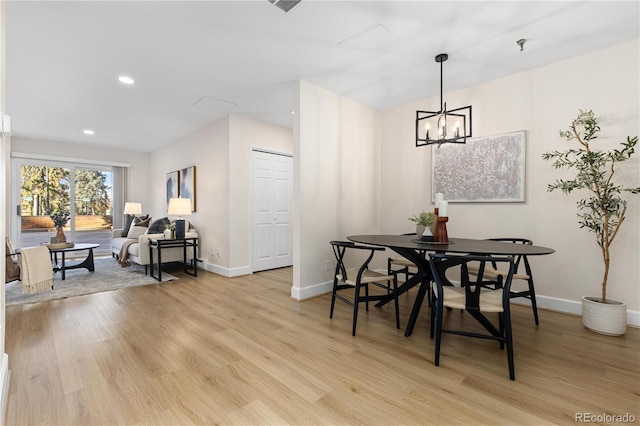 dining space with light hardwood / wood-style flooring and a notable chandelier