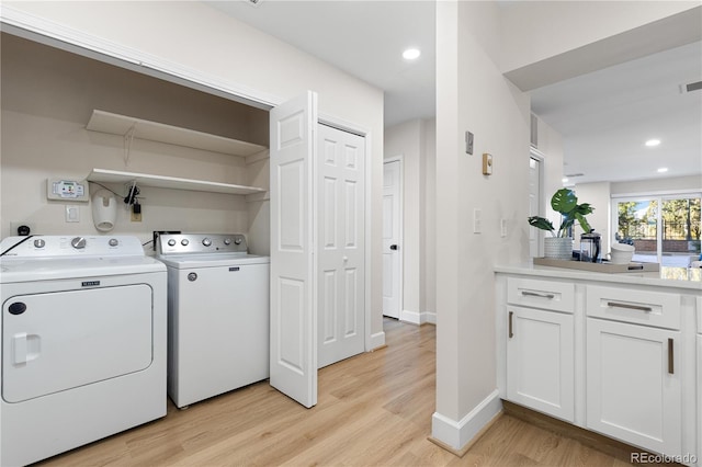 laundry area featuring washer and dryer and light hardwood / wood-style flooring