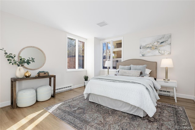 bedroom featuring wood-type flooring and a baseboard heating unit