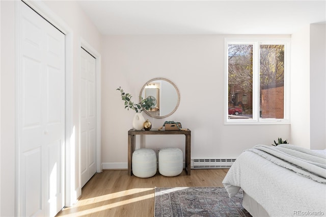 bedroom featuring baseboard heating and light hardwood / wood-style flooring