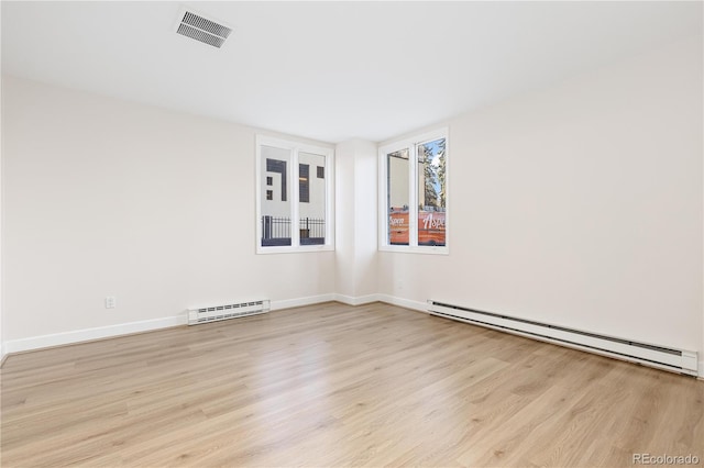 spare room featuring baseboard heating and light hardwood / wood-style flooring