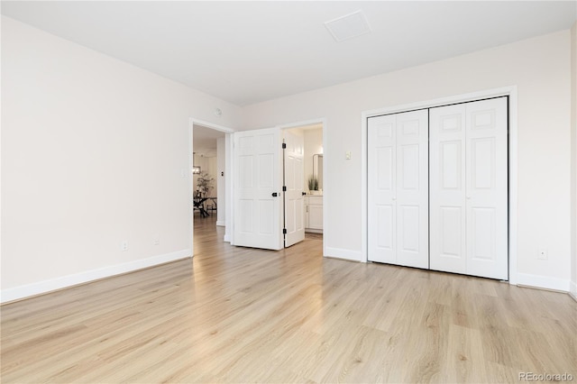 unfurnished bedroom with light wood-type flooring and a closet