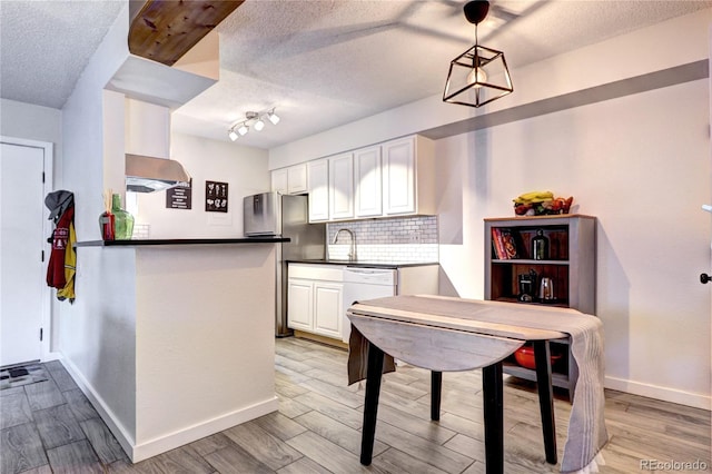 kitchen with a textured ceiling, white cabinets, tasteful backsplash, kitchen peninsula, and track lighting