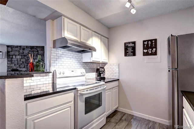 kitchen with white electric stove, wall chimney exhaust hood, stainless steel refrigerator, white cabinetry, and a textured ceiling