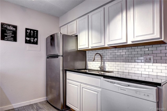 kitchen with backsplash, light hardwood / wood-style floors, dishwasher, white cabinetry, and sink