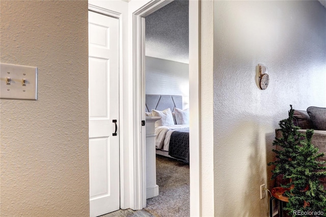 corridor featuring light colored carpet and a textured ceiling