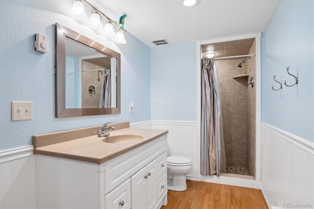 full bathroom featuring toilet, a shower stall, visible vents, wainscoting, and wood finished floors