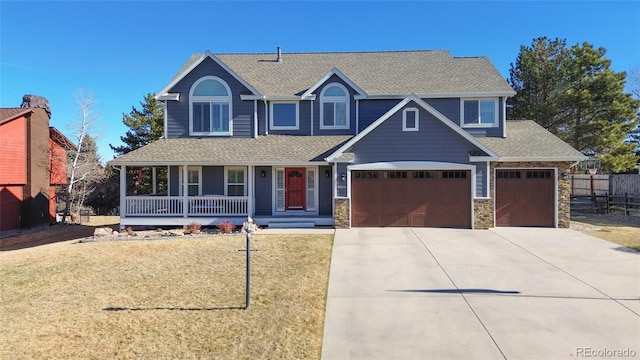 view of front of property with stone siding, a porch, concrete driveway, and a front lawn