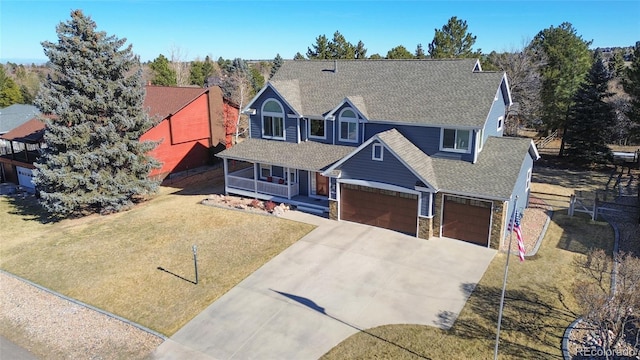 view of front of house featuring a shingled roof, a front lawn, a porch, concrete driveway, and an attached garage