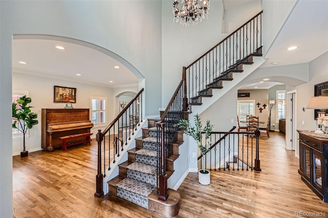 staircase with recessed lighting, wood finished floors, arched walkways, and baseboards