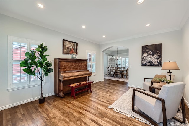 living area with wood finished floors, arched walkways, and ornamental molding