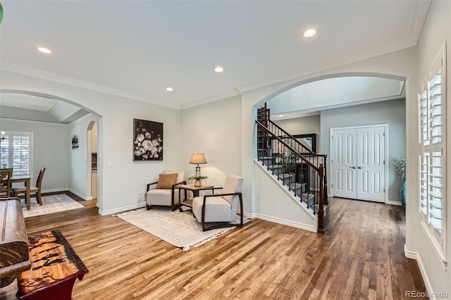 entryway with arched walkways, stairway, baseboards, and wood finished floors