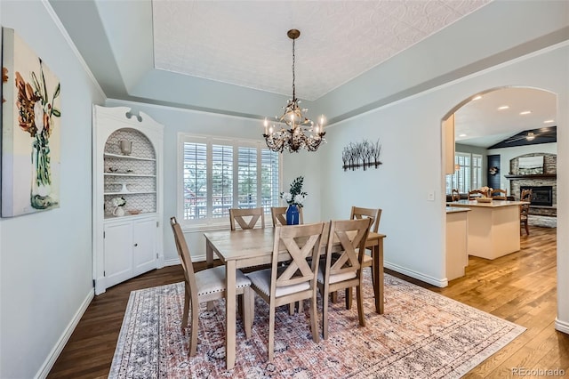 dining room with arched walkways, a healthy amount of sunlight, and wood finished floors