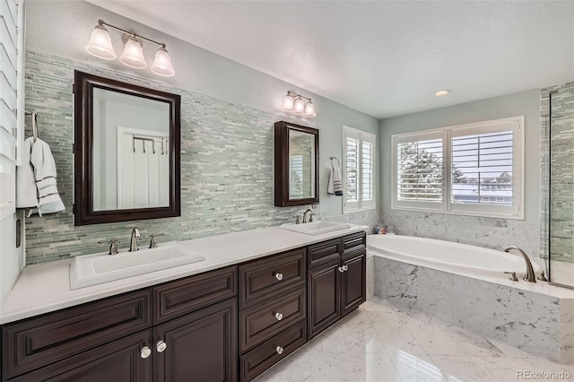 bathroom featuring double vanity, marble finish floor, a garden tub, and a sink