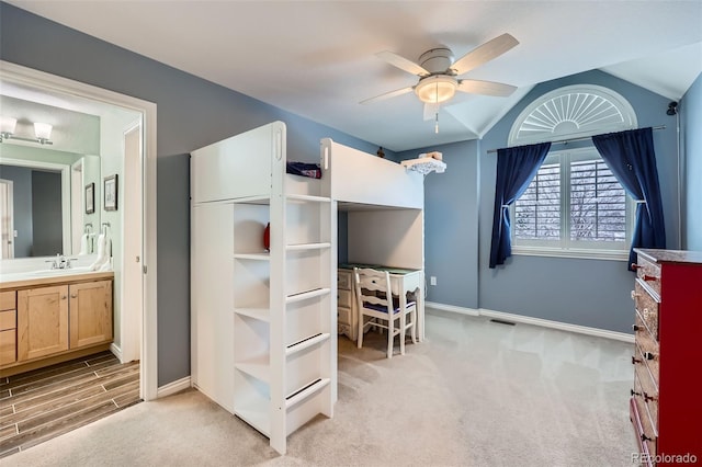 bedroom featuring visible vents, light carpet, a sink, baseboards, and vaulted ceiling