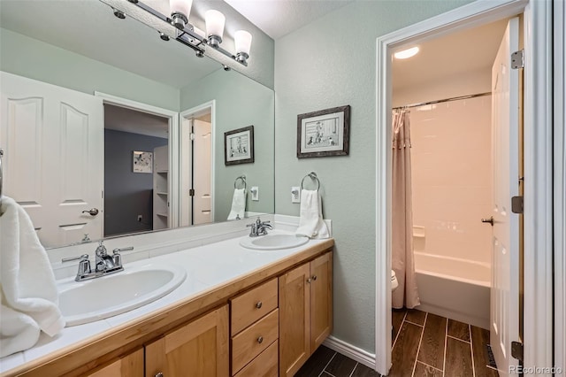 bathroom with double vanity, shower / tub combo, wood tiled floor, and a sink