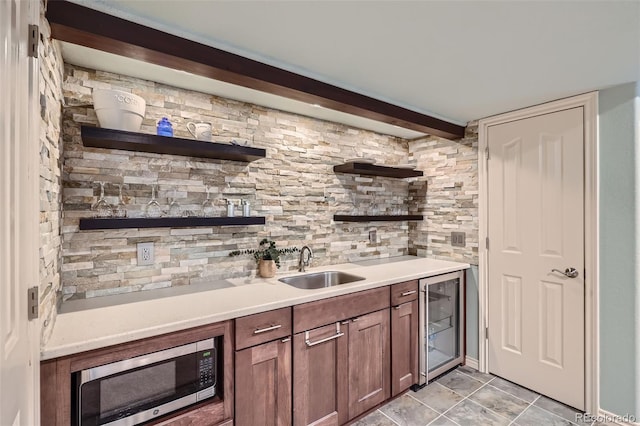 bar featuring stainless steel microwave, beverage cooler, beamed ceiling, light tile patterned floors, and a sink