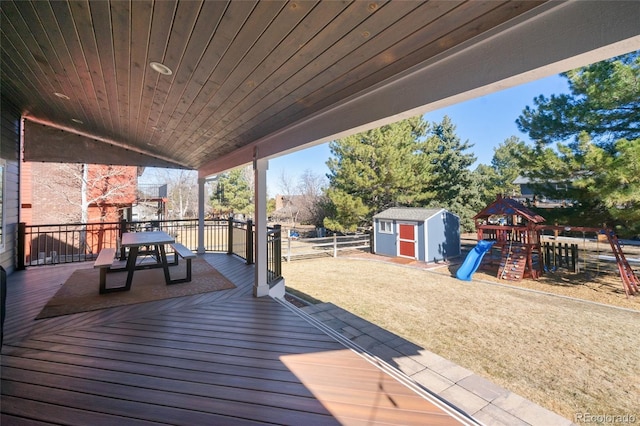 wooden terrace with a storage unit, a playground, an outdoor structure, and fence