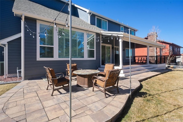 rear view of property featuring a patio, a fire pit, and roof with shingles