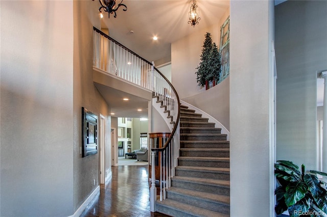 stairs with a high ceiling, hardwood / wood-style floors, and a chandelier