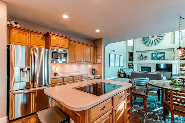 kitchen featuring a fireplace, a center island, appliances with stainless steel finishes, and dark hardwood / wood-style floors