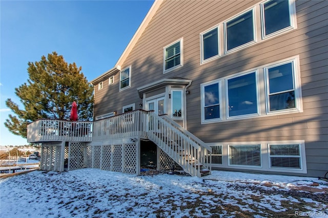 snow covered back of property featuring a wooden deck