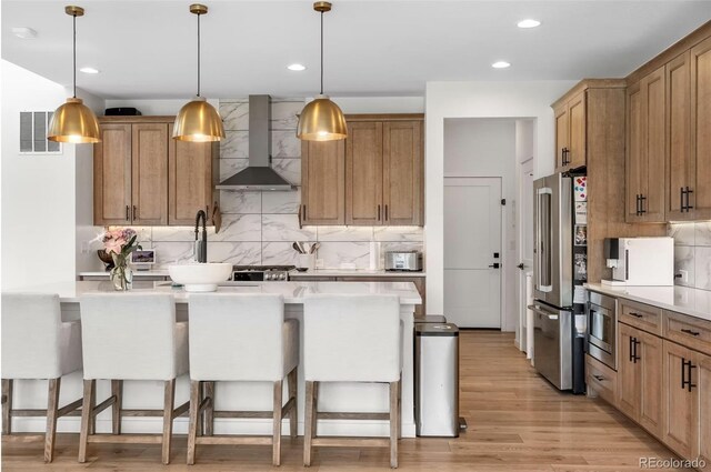 9140 Moondance Dr, Littleton, CO 80125 - kitchen with wall chimney exhaust hood, appliances with stainless steel finishes, a kitchen breakfast bar, tasteful backsplash, and recessed lighting